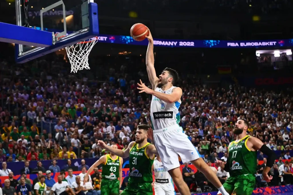 Basketballspieler springt zum Korbwurf mit gegnerischer Mannschaft in der Abwehr