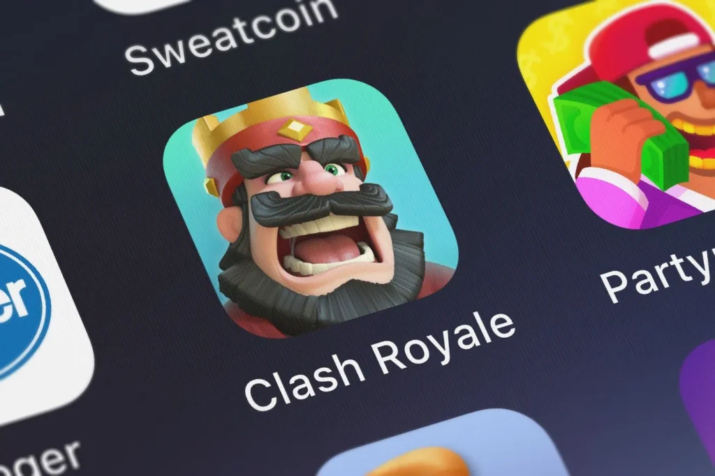 Logo des Mobile-Games Clash Royale auf dem Display eines Smartphones neben Logos von weiteren Spielen